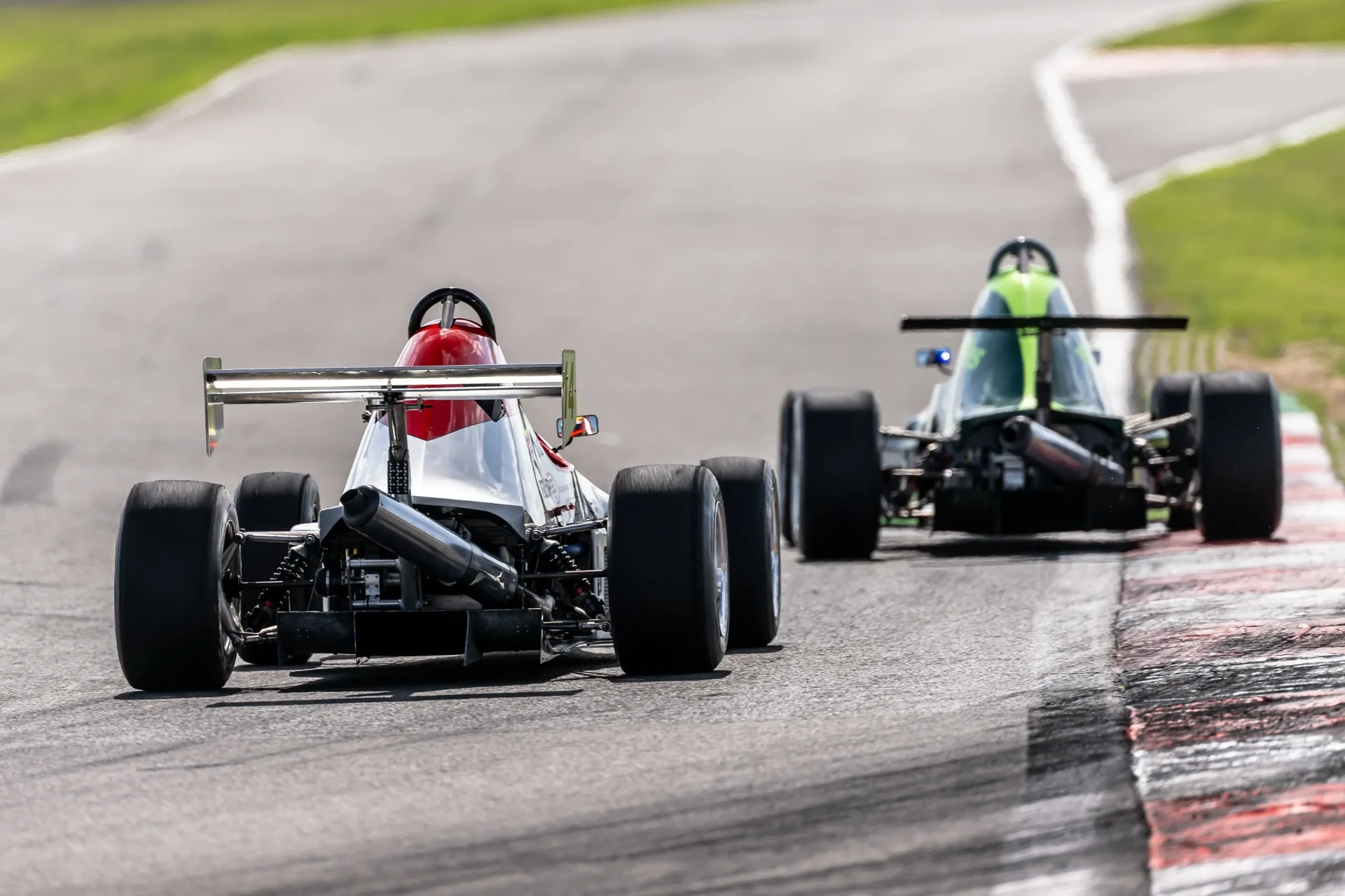Two race cars racing closely together, viewed from behind