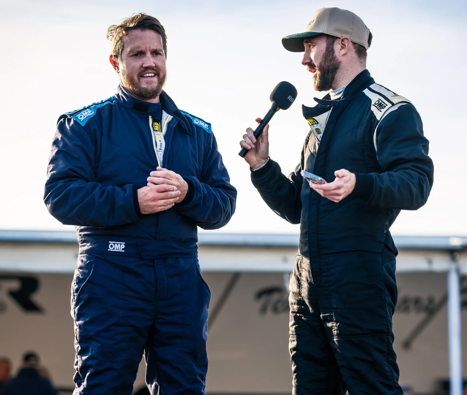Two drivers in racing suits recording a paddock interview