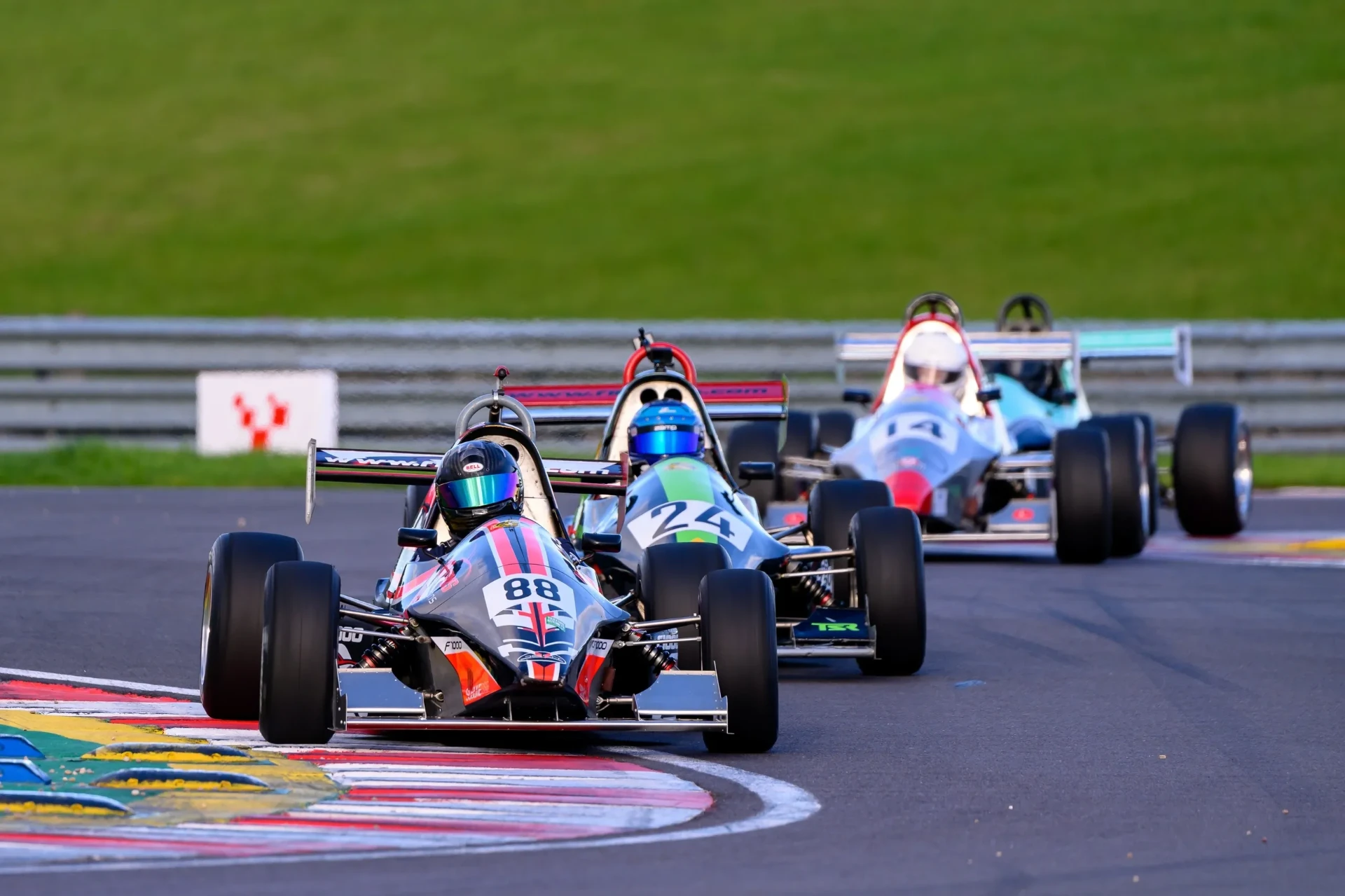 A group of race cars following each other through a corner